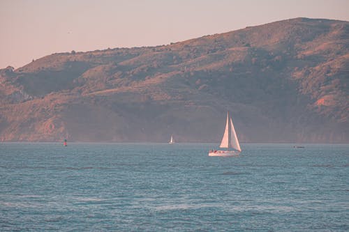 A sailboat is sailing in the ocean near a mountain