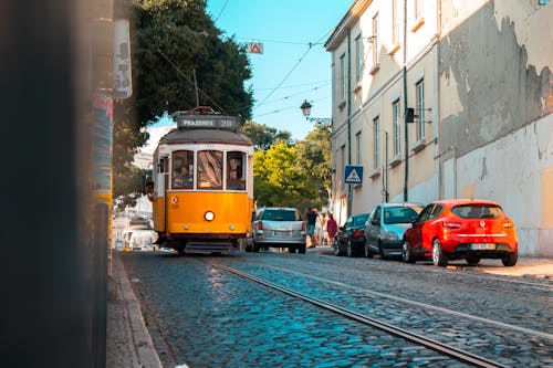 A yellow tram is driving down a street