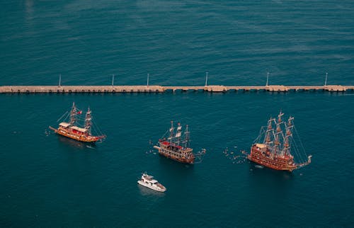A group of ships in the water near a pier