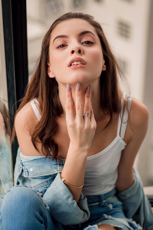 Free Photo of Woman in White Top and Denim Outfit Posing With Her Fingers Under Chin Stock Photo