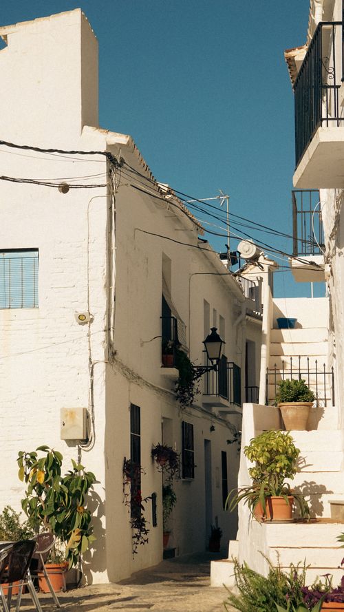 Free Serene alleyway with whitewashed buildings in Mediterranean town under clear blue sky. Stock Photo
