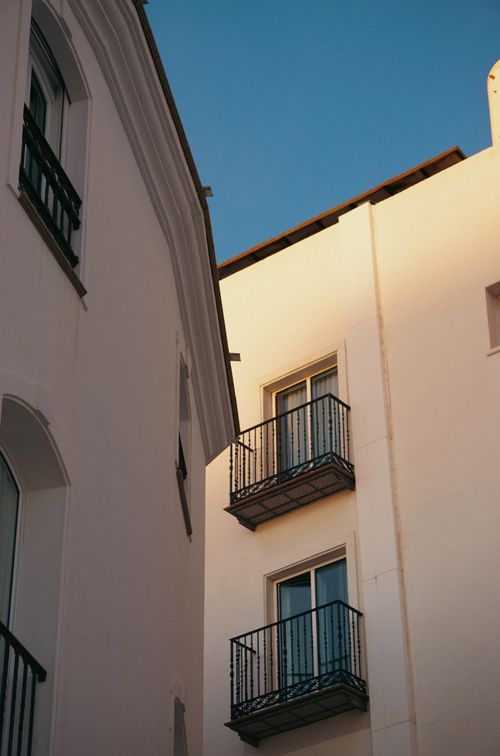 Free A minimalistic view of modern white buildings with balconies under a clear blue sky. Stock Photo