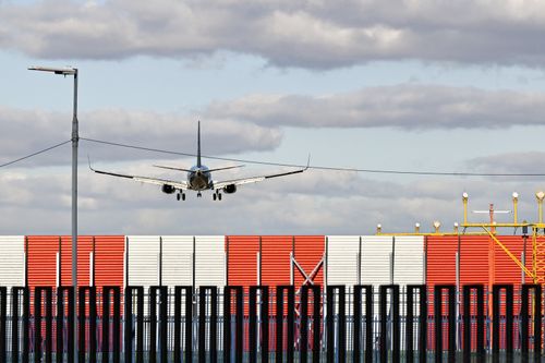 Free Commercial airplane descends at Buenos Aires airport with striped fence and cloudy sky. Stock Photo