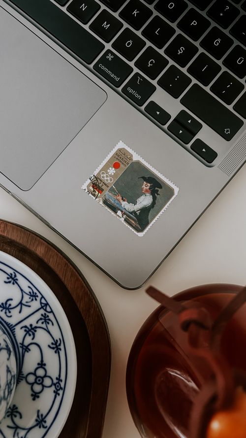 Free Top view of a laptop with a unique sticker and tea on a stylish desk setup. Stock Photo