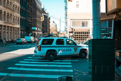 Free A police SUV at an urban intersection in New York City with pedestrians and traffic. Stock Photo