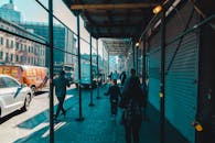 阳光明媚的日子里，城市街景显示，人们在建筑脚手架下开着车行走