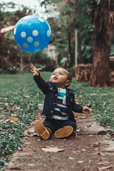 可爱的男婴在公园里伸手去拿蓝色气球，捕捉到欢乐和嬉戏