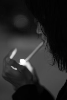 Artistic black and white portrait of a person smoking, highlighting dramatic lighting.