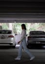 A woman walking through a parking garage with cars parked in the background