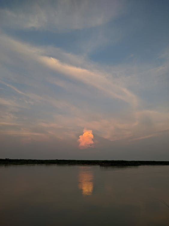 A sunset over the river with clouds in the sky