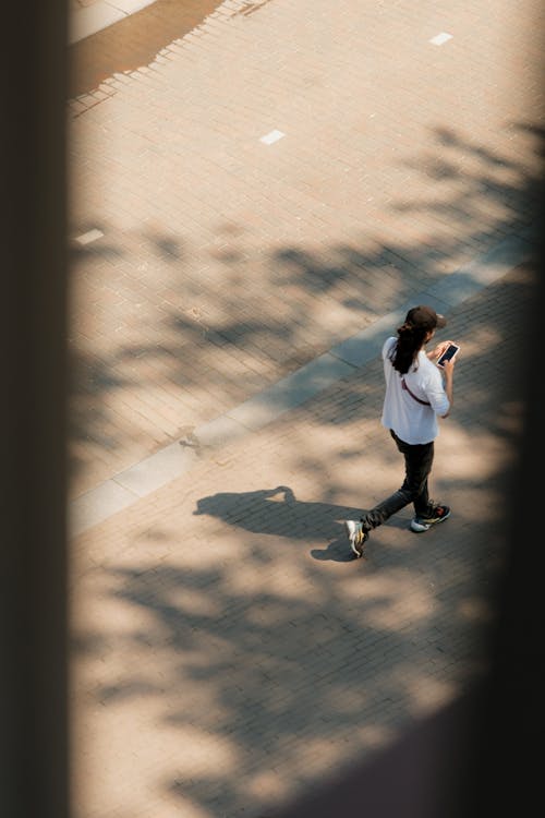 A person walking down a sidewalk with a cell phone