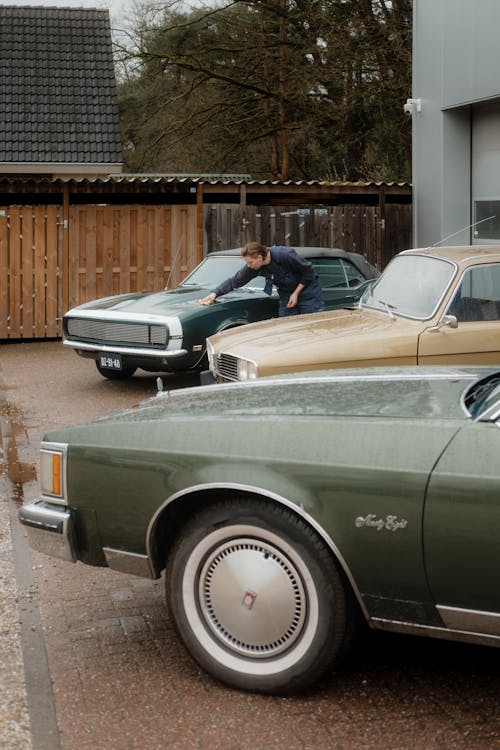 A man is looking at a car parked in front of a garage