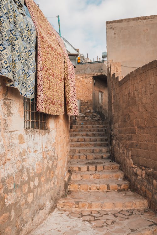 A narrow alley with rugs hanging from the walls