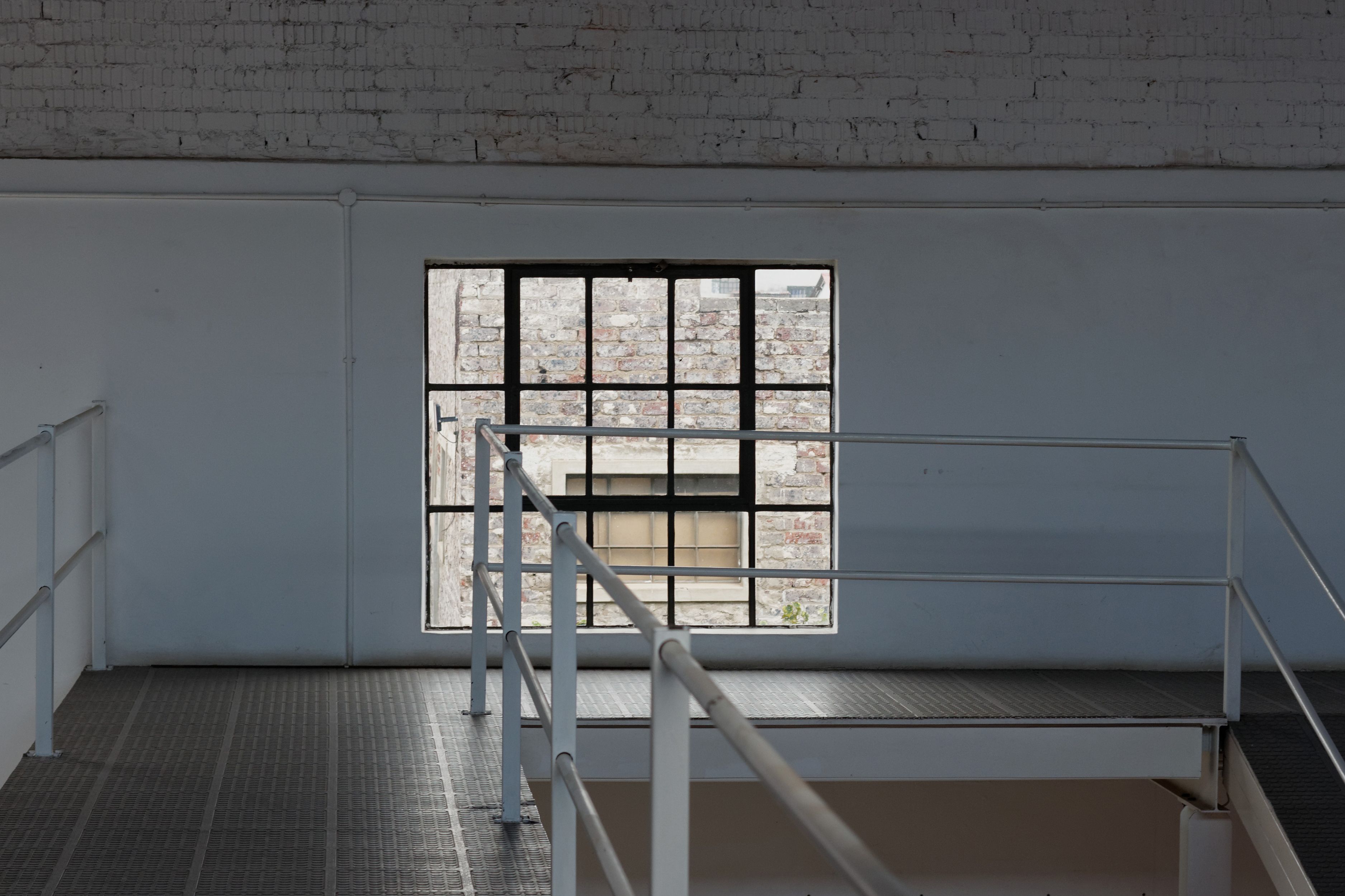 A minimalist industrial interior featuring a metal railing and large window in Johannesburg, South Africa.