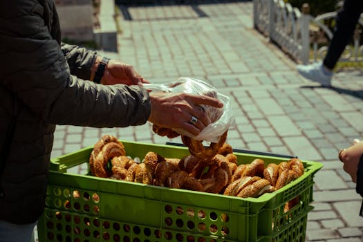 Captivating image of a street vendor arranging freshly baked Turkish simit in a green basket on a bustling market street.