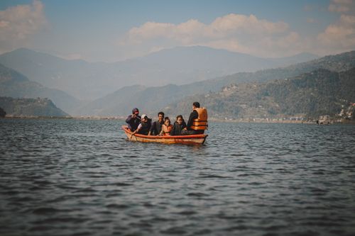 Free A group of people enjoying a boating trip on a serene lake with mountainous background. Stock Photo
