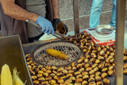 Street vendor grilling corn and chestnuts at an outdoor market.