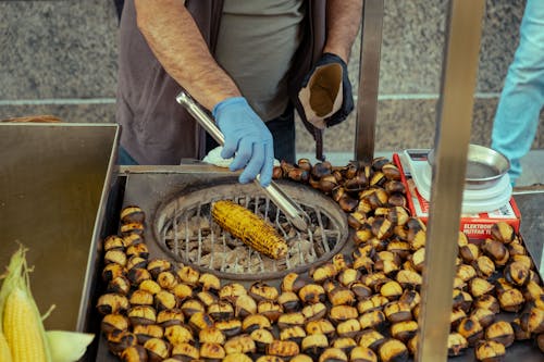A man is cooking corn on a grill
