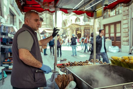 An urban street vendor preparing roasted chestnuts and corn in a bustling city setting.
