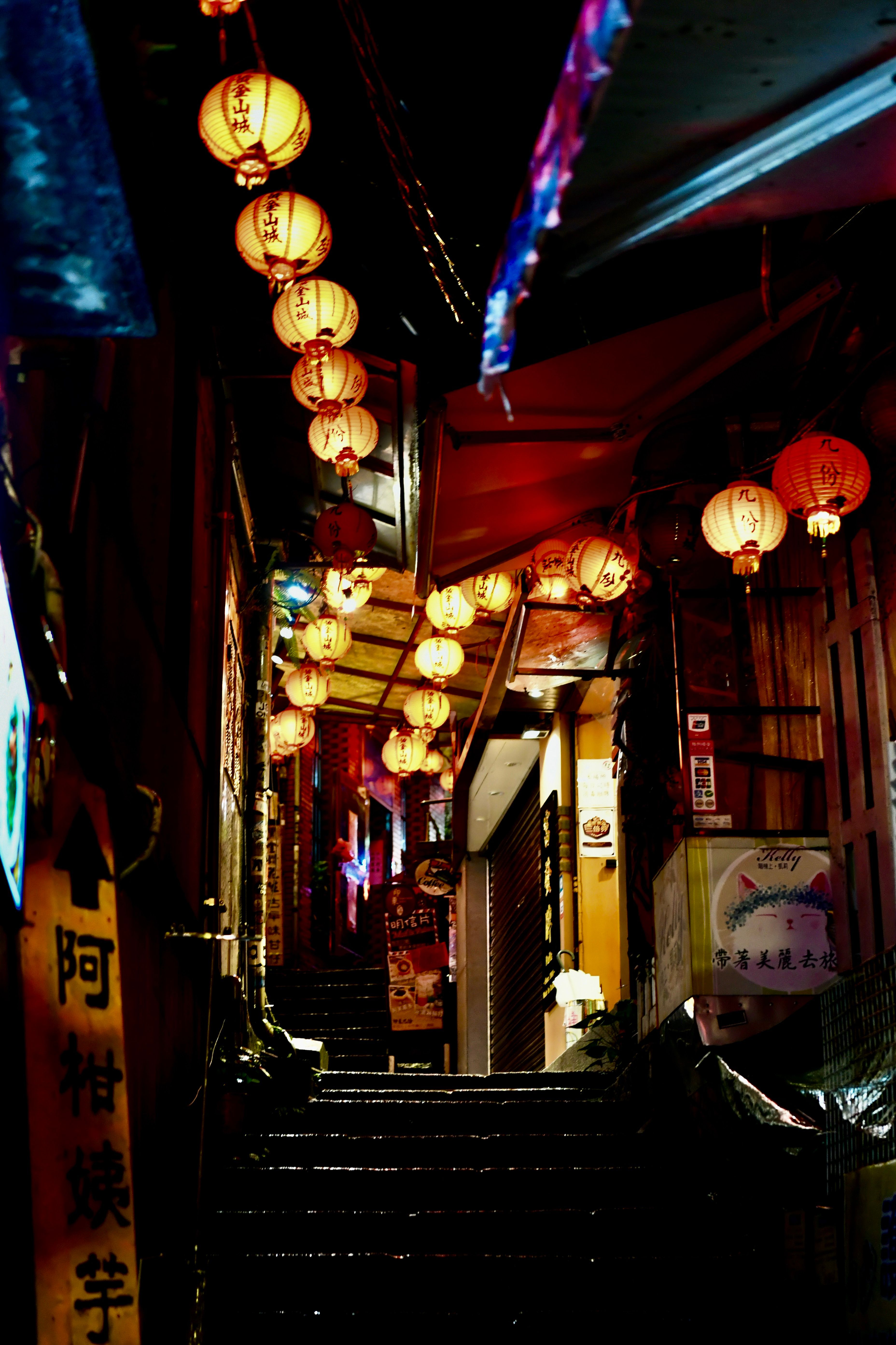 A narrow alley with lanterns hanging from the ceiling · Free Stock Photo