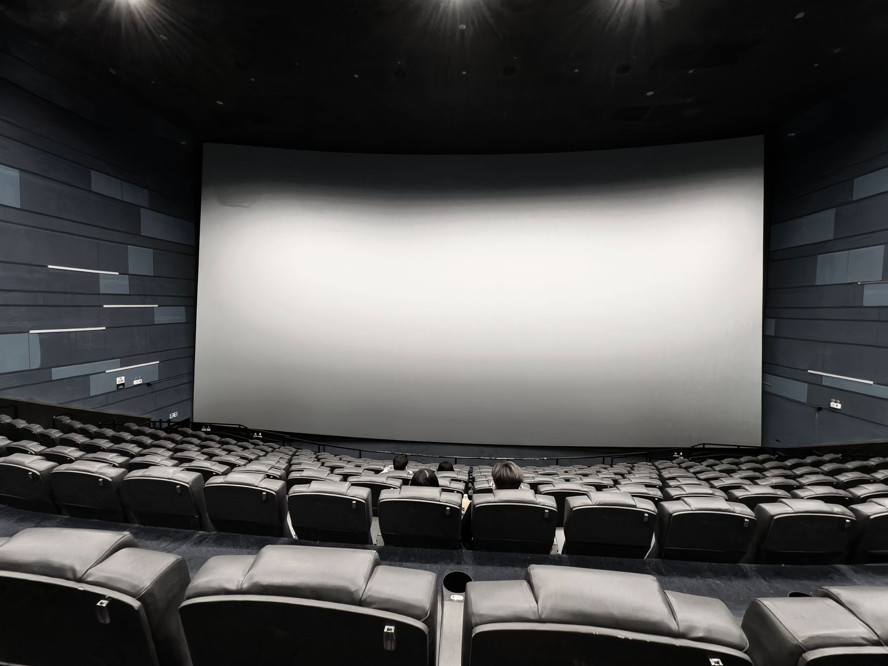 Interior shot of an IMAX 70mm film projector platter and projection glass looking into a large empty IMAX movie auditorium.