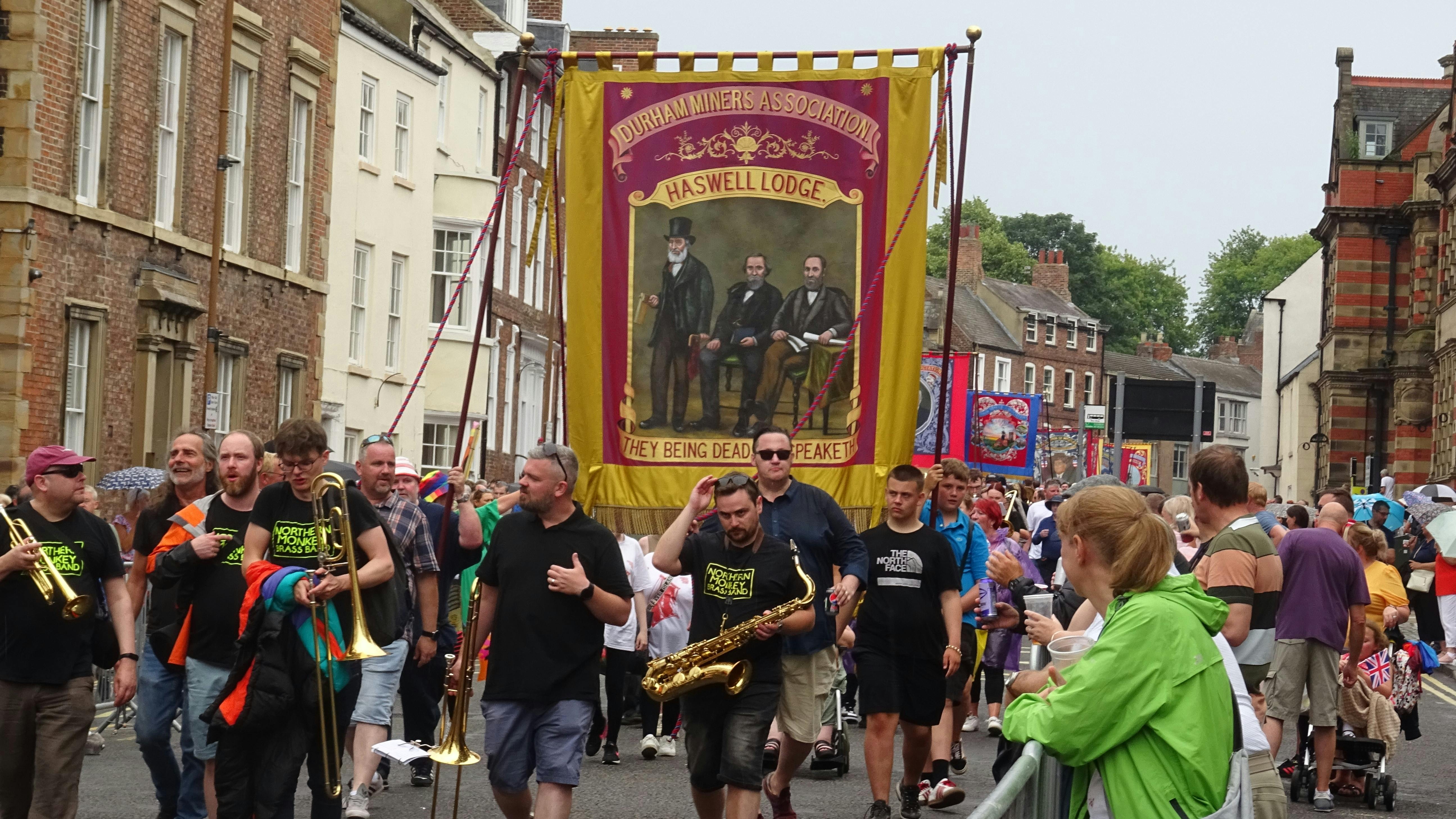 Vibrant parade at Durham Miners' Gala with musicians and banners in the city center.