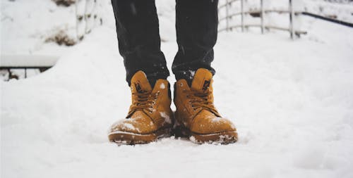Free Person Wearing Pair of Brown Leather Work Boots Stepping on the Snow Stock Photo