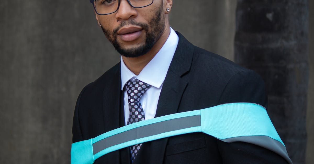 Smiling graduate sitting outside wearing a cap and gown with stole.