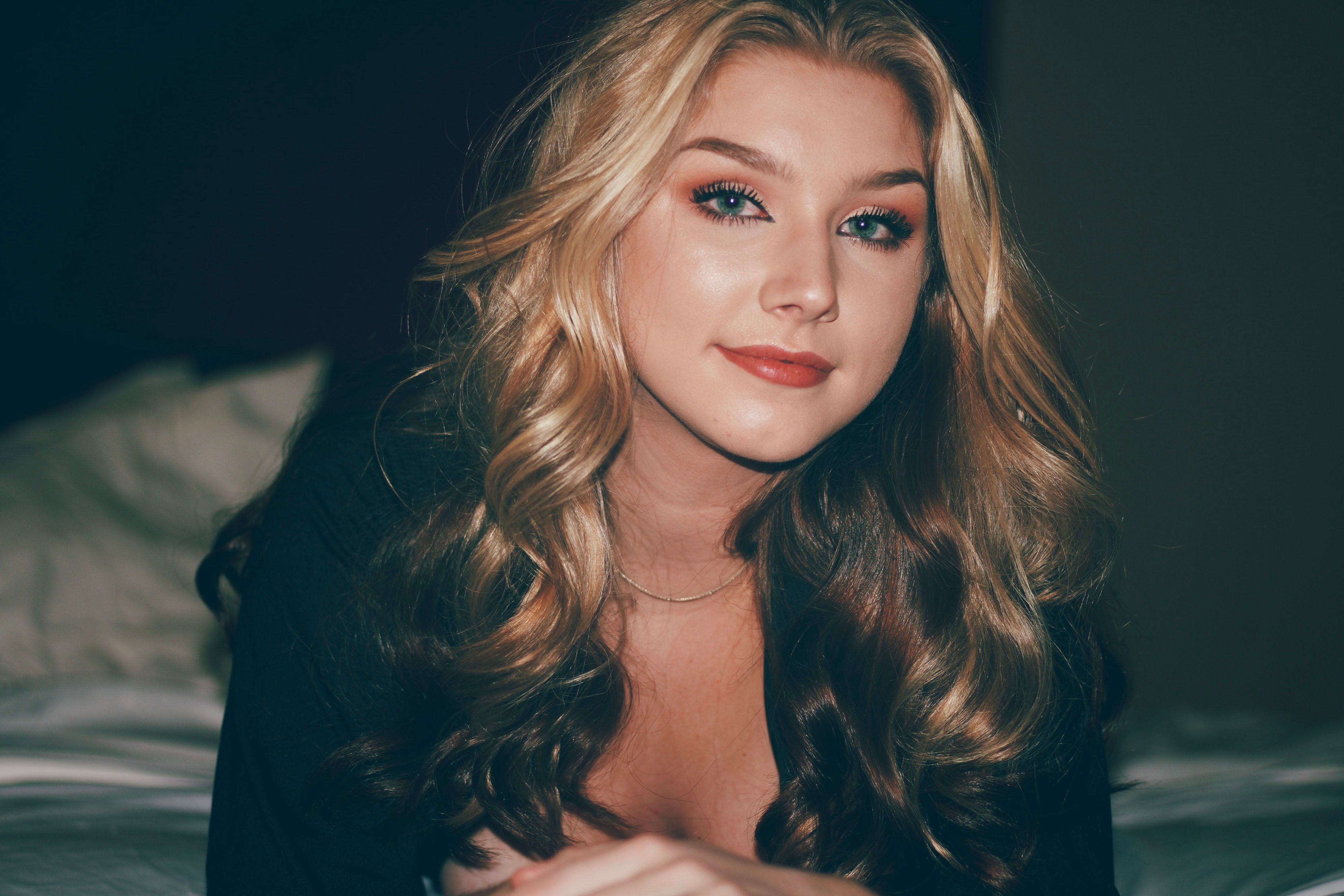 Portrait of a young blonde woman posing with a confident smile indoors.