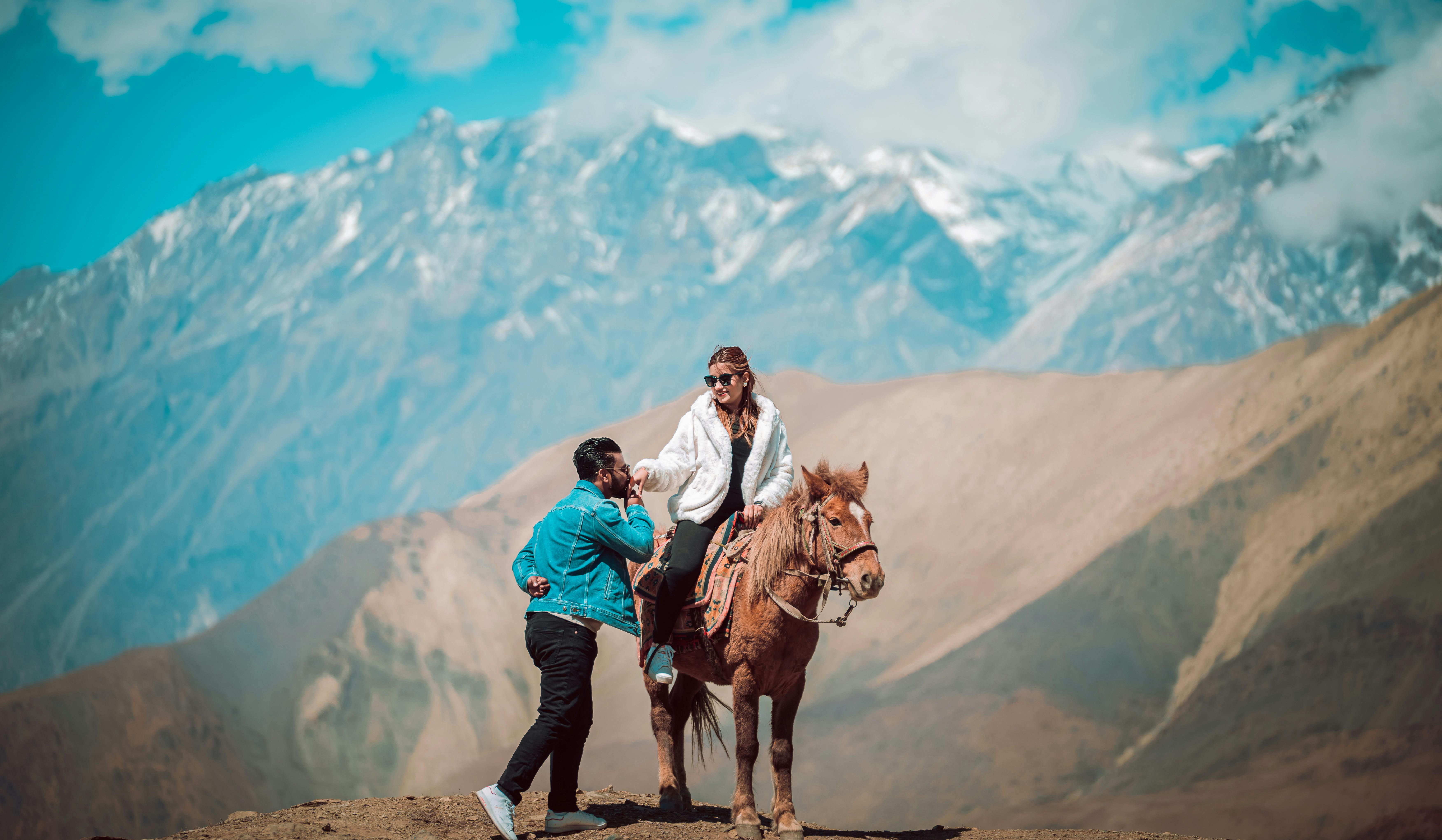 A couple shares a moment in breathtaking mountain scenery with a horse ride.