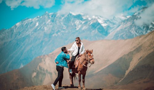 Two people on a horse in the mountains