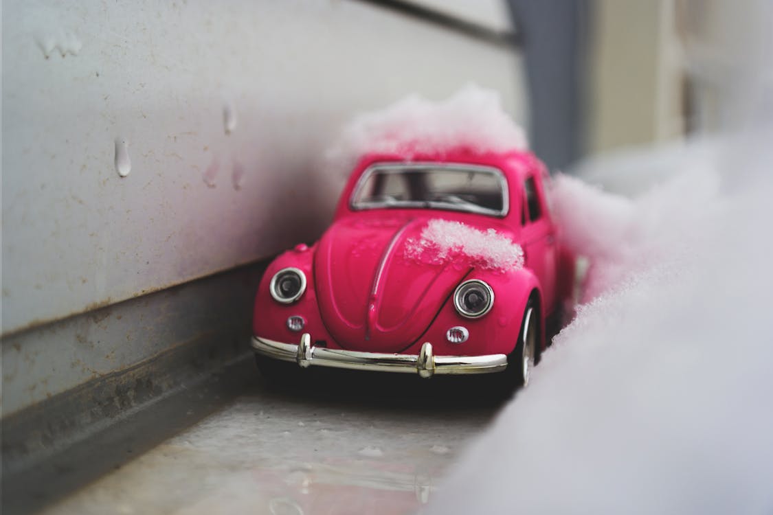 Free Red Volkswagen Beetle Die-cast Metal Model Beside White Wall Stock Photo