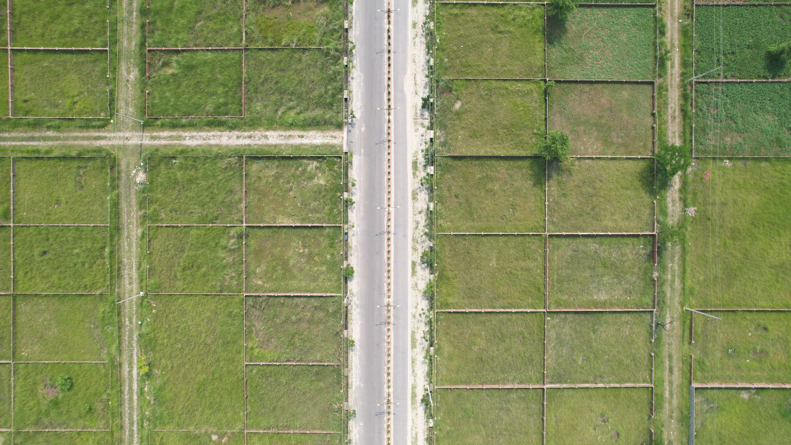 Vista cenital de una lotización con calle asfaltada y lotes ya delimitados, todavía sin construir.
