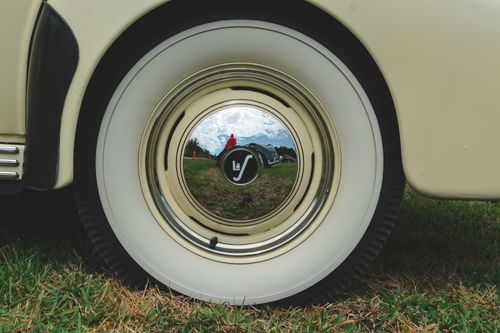 Free A detailed close-up of a vintage car's wheel reflecting a clear outdoor scene. Stock Photo