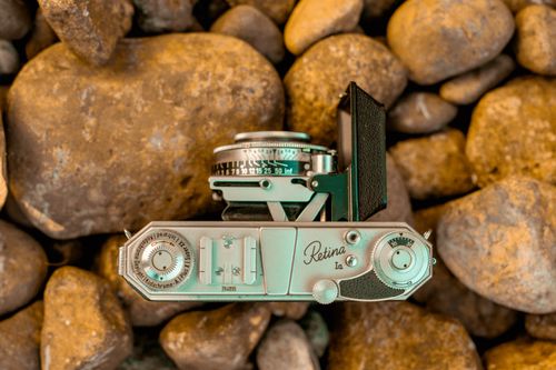Free A top-down view of a vintage camera placed on natural rocks, emphasizing a retro and classic aesthetic. Stock Photo