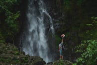 一名男子在壮观的丛林瀑布旁拥抱冒险，庆祝大自然