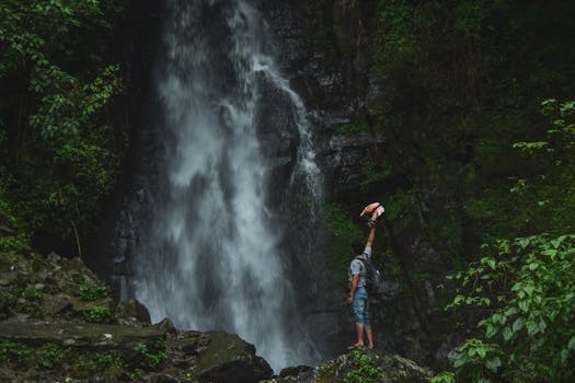 一名男子在壮观的丛林瀑布旁拥抱冒险，庆祝大自然