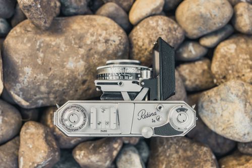 Free Top view of a classic vintage camera on rustic stones, evoking nostalgia and timelessness. Stock Photo