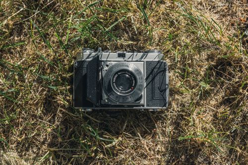 Free A classic vintage film camera rests on dry grass, capturing the essence of retro photography. Stock Photo