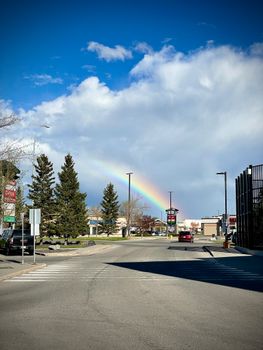 A bright rainbow arches over a quiet urban street in Calgary, lending a pop of color to the cityscape.
