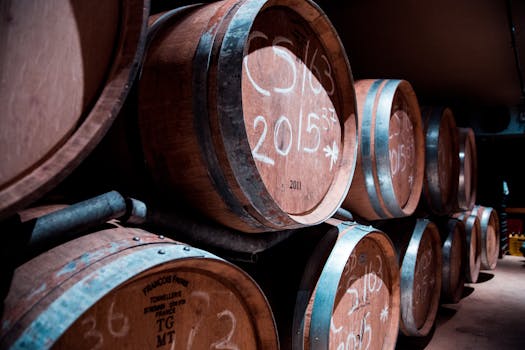 A dimly lit cellar in Stellenbosch, South Africa, showcasing stacked wooden wine barrels.