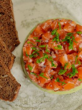 Delicious salmon tartare topped with herbs, served with rye bread slices. Perfect for gourmet appetizers.
