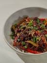 A bowl of noodles with meat and peppers
