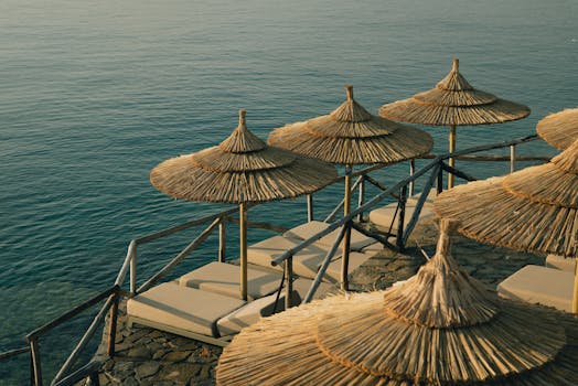 Relaxing beachside view with straw umbrellas and sunbeds by the sea, perfect for a summer getaway.