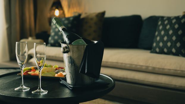 Elegant indoor setup featuring champagne and fruits on a table, exuding luxury and relaxation.
