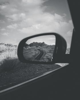 Artistic photo capturing desert landscape in car side mirror, creating a moody travel vibe.