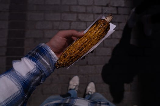 Street scene in Istanbul featuring a hand holding grilled corn under nighttime lighting.