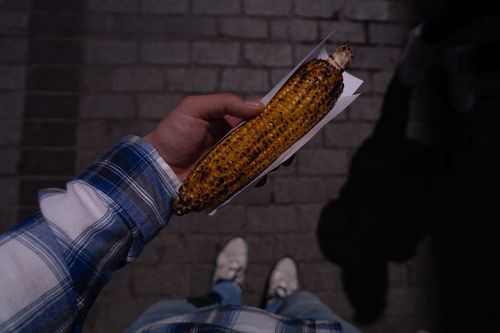 Free Street scene in Istanbul featuring a hand holding grilled corn under nighttime lighting. Stock Photo