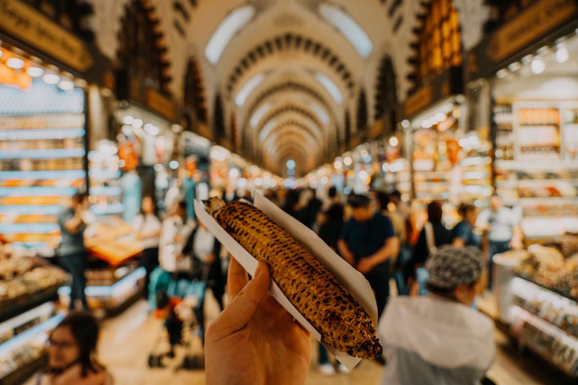 A person holding a corn on the cob in a market