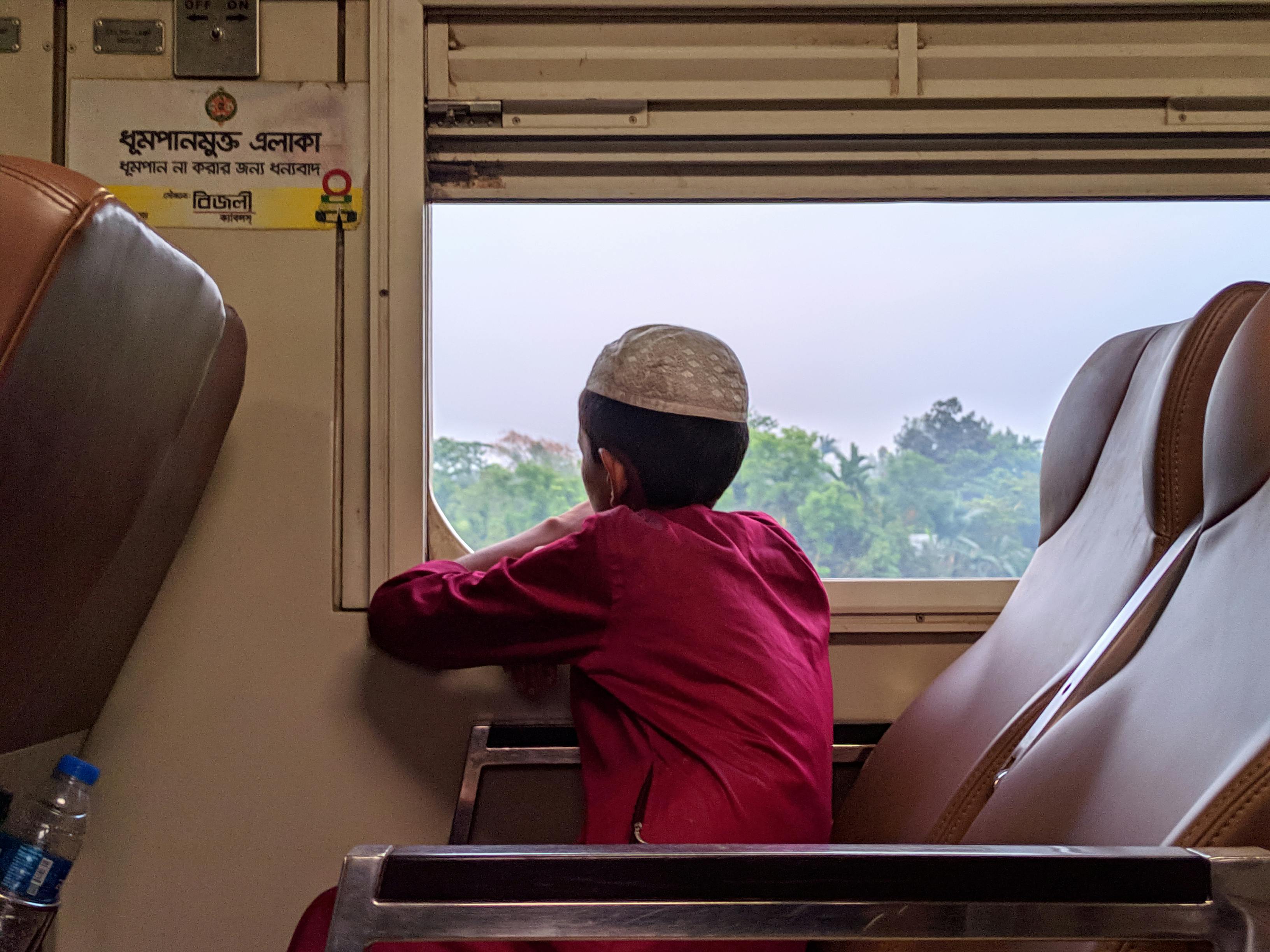 Free A young boy gazes out of a train window in Lalmonirhat, Bangladesh, capturing travel moments. Stock Photo